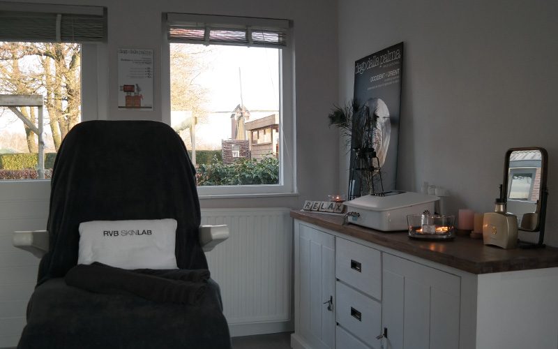 De rustige behandelruimte van Evelien Schoonheidssalon met behandelstoel en uitzicht op de molen van Geffen