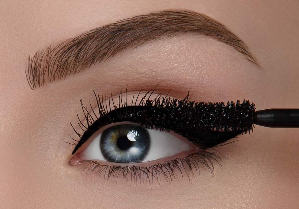 Close-up van een oog waarbij mascara wordt aangebracht vanaf de wimperrand